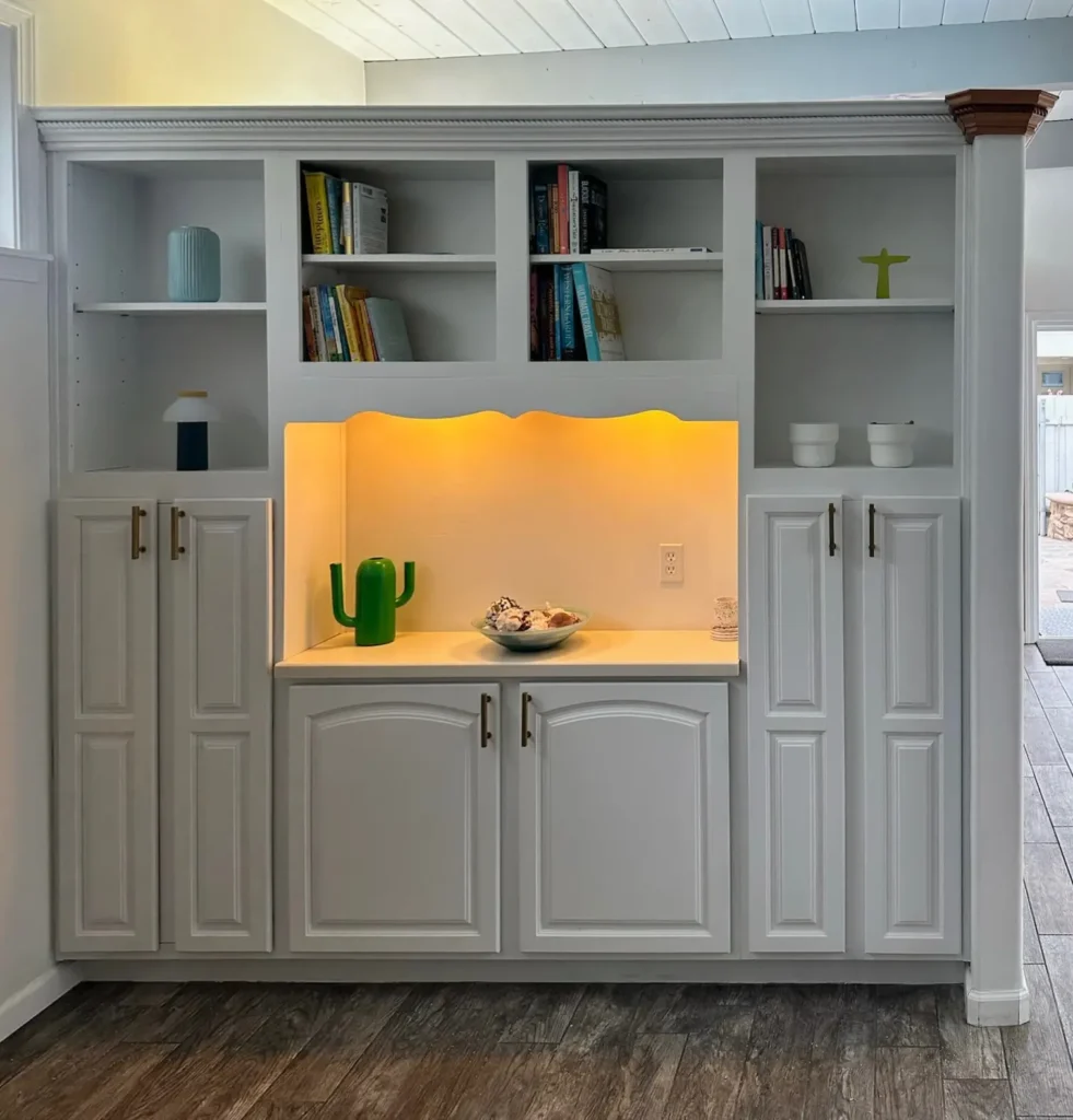 Built-in cabinetry freshly painted white with newly installed warm LED accent lighting in the center display area.